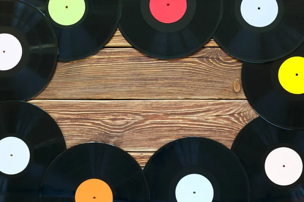 Retro-Schallplatten auf Holztischhintergrund. Bunte Etiketten. Ansicht von oben. Platz zum Kopieren von Raum. Stockbild