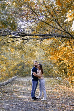 Genç çift parkta birbirine sarılıyor. Bir erkek ve bir kadın baş başa. Ormanda ılık bir sonbahar akşamı.