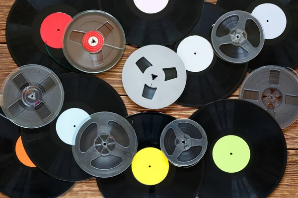 Old vintage bobbins and vinyl records on a wood table background. Multicolored labels. Top view. — Stock Photo, Image