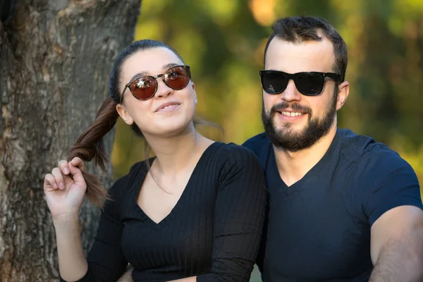 Portret mężczyzny i kobiety w okularach przeciwsłonecznych w lesie. Młoda stylowa para na tle natury. Ciepły jesienny wieczór w lesie. — Zdjęcie stockowe