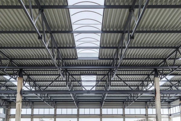 Techo de aluminio con ventanas en un marco de metal. Dos vigas de hormigón armado sostienen la estructura. Construcción del hangar . — Foto de Stock