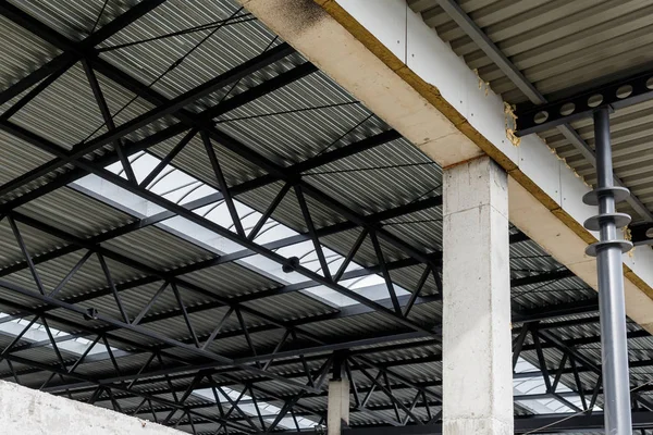 Techo de aluminio con ventanas en un marco de metal. Las columnas de hierro soportan la visera. Construcción del hangar . — Foto de Stock