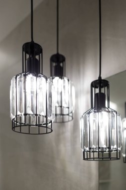 Tavan lambası. Modern üç lamba avizesi. Banyoda lamba var. Aynaya yansıyor. Dikey çerçevelenmiş çekim.