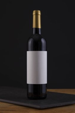 Bir siyah, ahşap arka plan ve beyaz etiket izole kırmızı şarap şişe