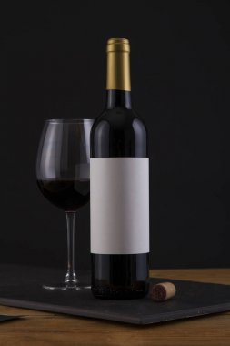 Bir siyah, ahşap arka plan ve beyaz etiket izole kırmızı şarap şişe