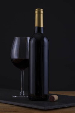 İzole kırmızı şarap şişe bir siyah, ahşap arka plan ve etiket yok
