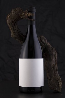 Bir asma ile siyah bir arka plan izole kırmızı şarap şişesi