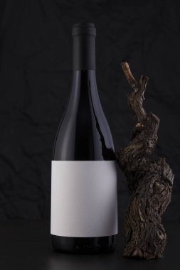 Bir asma ile siyah bir arka plan izole kırmızı şarap şişesi