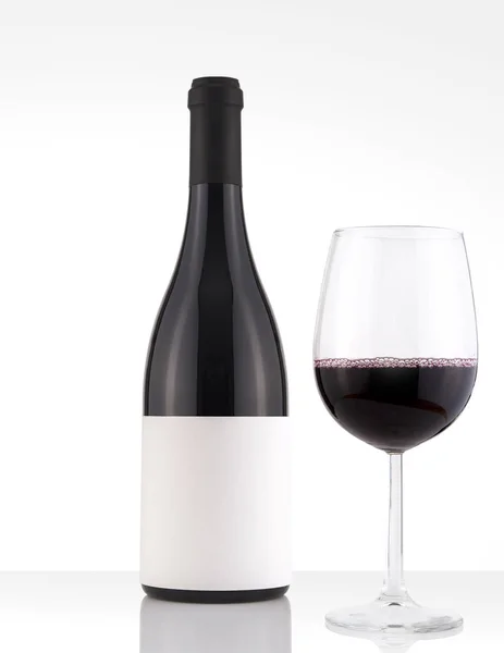 Botella aislada de vino tinto en un fondo blanco, etiqueta blanca y vidrio — Foto de Stock