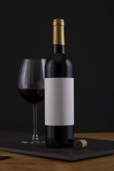 Isolated Red Wine Bottle in a Black, wood Background and White Label — Stock Photo, Image