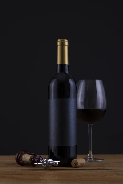 Botella aislada de vino tinto en un fondo negro y etiqueta — Foto de Stock