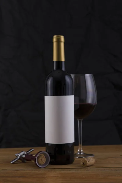 Garrafa de vinho tinto isolado em um fundo preto e vidro — Fotografia de Stock