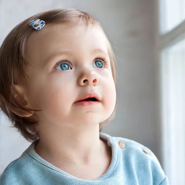 Gadis kecil dengan mata melamun melihat ke luar jendela — Stok Foto