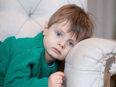 Güzel mavi gözlü çocuk kanepede yatan ve üzgün ara arama