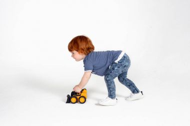 Kızıl saçlı küçük çocuk sarı oyuncak traktör ile oynamak