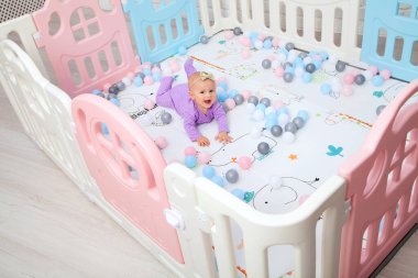 Mor takım elbiseli küçük kız çocuk parkında yatıyor ve gülümsüyor.