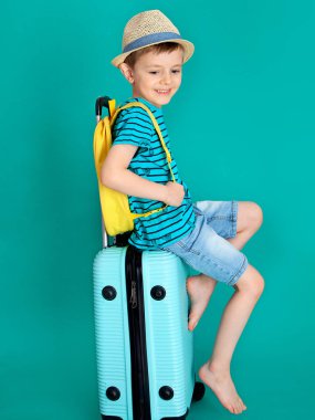 Şapkalı bir gezgin mavi bir bavula çıplak ayakla oturmuş ve rüyalar görüyor.