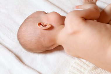 Bebek beyaz bir yatakta yan yatar. Bize arkasını döndü, gözleri kapalı ve uykusunda gülümsüyor. Bebeğini nasıl uyutacağını. Yatmaya hazırlanıyorum. Uyku ve dinlenme ürünleri.