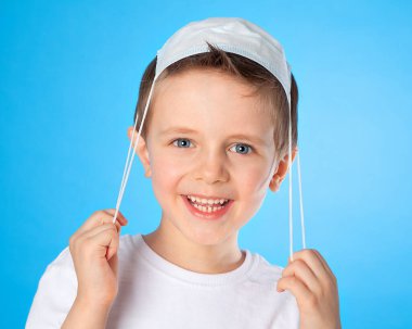 Güzel bir Avrupalı çocuk tıbbi bir maskeyle oynuyor. Kafasının üstüne koyup gülüyor. Oyun hastanede, doktor da öyle. Çocuk çok mutlu. Coronavirus 'a karşı zafer.