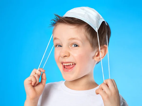 A five-year-old boy plays with a medical mask-he puts it on top of his head and laughs and grimaces. Laughter, fun, joy, happiness. The game is in the hospital, the doctor. Convalescence.