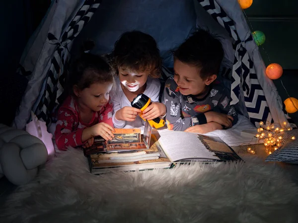 Троє Дітей Сидять Наметі Вночі Читають Допомогою Ліхтарика Цікаву Книгу Ліцензійні Стокові Фото