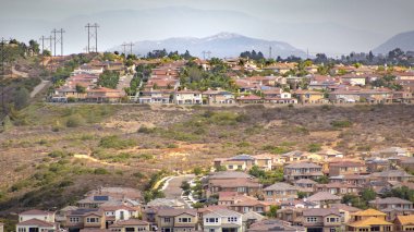 Houses on hill in front of mountain clipart