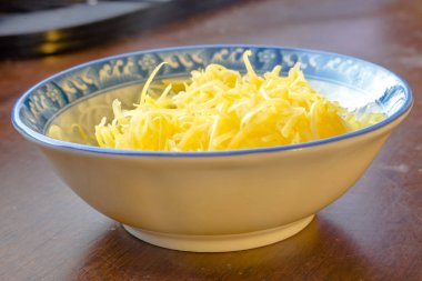 Rendelenmiş mozzarella ve kaşar üzerinde ahşap tabak içinde peynir