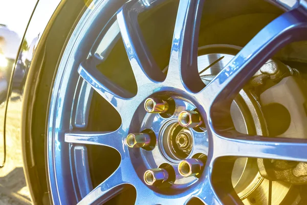 Blue rims with golden bolts on a black reflective car and sun bu — Stock Photo, Image