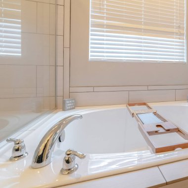 Ahşap tepsi taşıyıcısı olan kare modern spa banyosu.