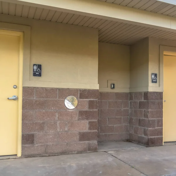 Square frame Public restroom at a golf course with white doors and concerete and brick wall — Stock Photo, Image