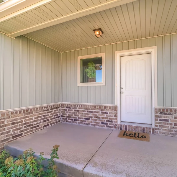 Square Front door and porch of home with welcome mat