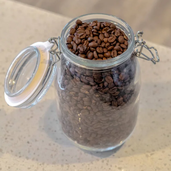 Square frame Open glass jar of fresh roasted coffee beans