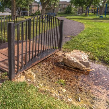 Güneşli bir günde, göl ve dağ manzaralı sığ derenin üzerindeki köprüyle kare kare kare parkı.