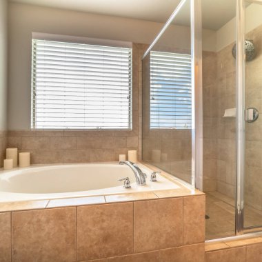 Dairesel küvette yapılmış kare çerçeve bir evin banyosunun içindeki duş kabininden ayrılır.