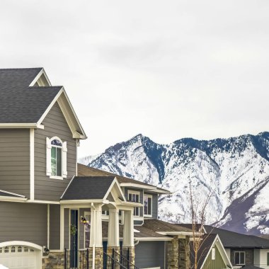 Kışın karlı dağlık ve bulutlu arka planlı güzel gri evler.