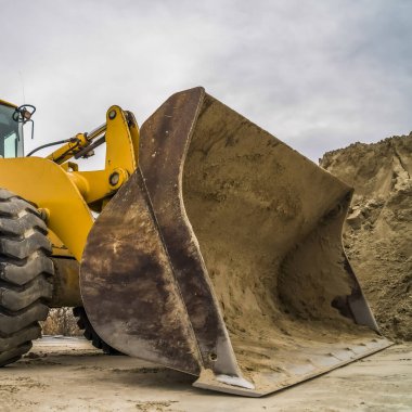 Kirli metal kovası ve siyah lastik tekerlekleri olan sarı bir buldozerin kare kare çerçeve manzarası