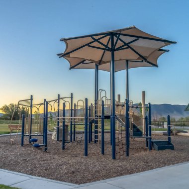 Gün batımında çocuk parkında gökyüzüne karşı kayar ve tırmanır.