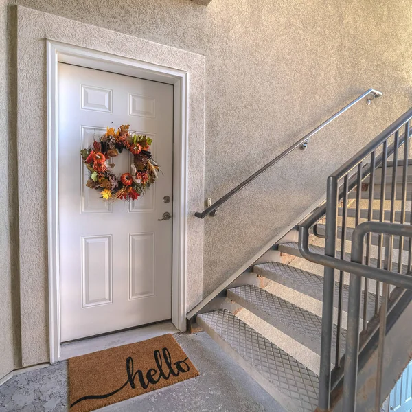 Square Apartment front door with welcome mat and wreath