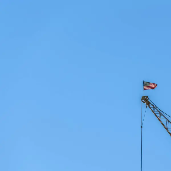 Vierkant frame Close-up van een kraan op een bouwplaats met helderblauwe lucht achtergrond — Stockfoto