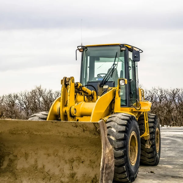 Bir inşaat alanında kirli kovası ve tekerlekleri olan sarı bir buldozer üzerine odaklanın. — Stok fotoğraf