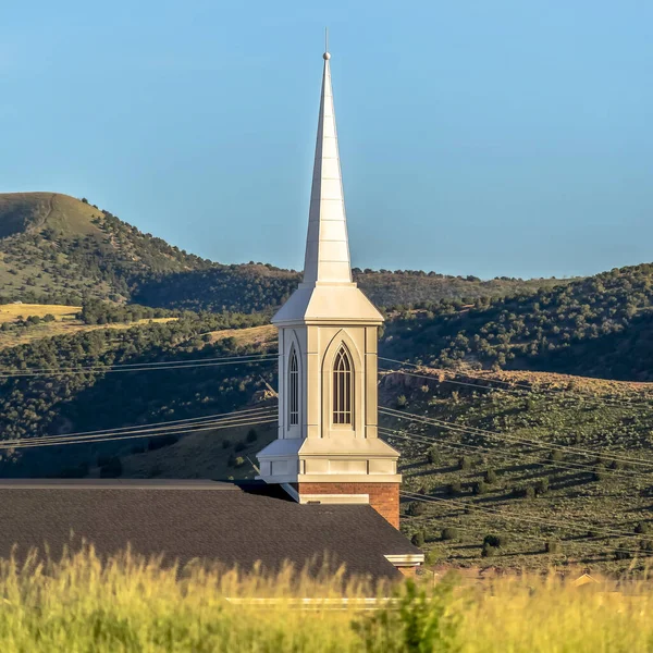 Cadre carré Toit et clocher d'une église avec fond de montagne et ciel bleu pâle — Photo