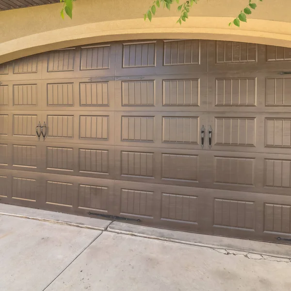 Porta da garage quadrata con un design ad arco contro il muro di cemento e mattoni di una casa — Foto Stock