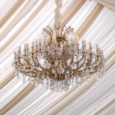 Bir düğün salonunda kristalleri ve sahte mumları olan kare güzel avize.