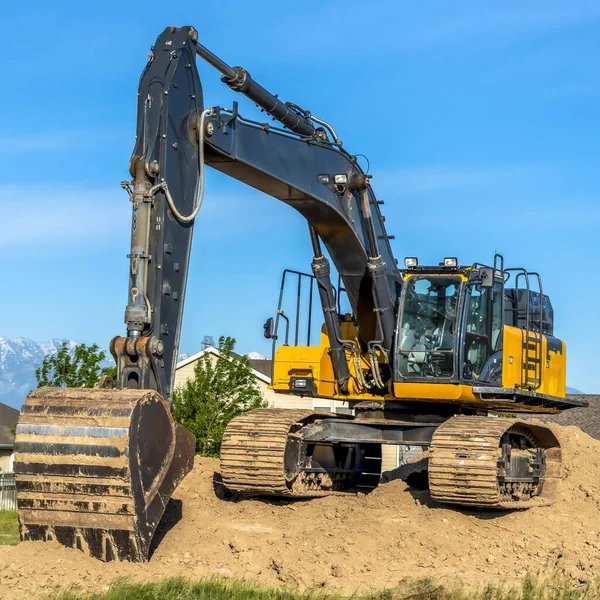 Square frame Close up of an excavator with arm bucket and continuous tracks on top of soil — Stock Photo, Image