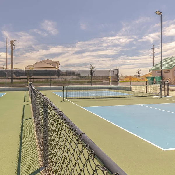 Marco cuadrado Canchas de tenis vacías en día soleado dividido por valla — Foto de Stock