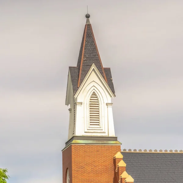 Square frame Side view of church exterior with focus on steeple and roof against cloudy sky — Stock Photo, Image