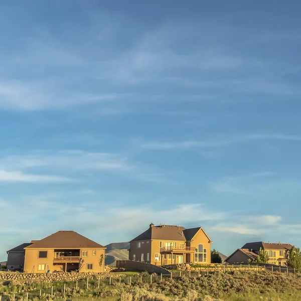 Cielo azul cuadrado y nubes sobre casas y colinas cubiertas de hierba vistas en un día soleado — Foto de Stock