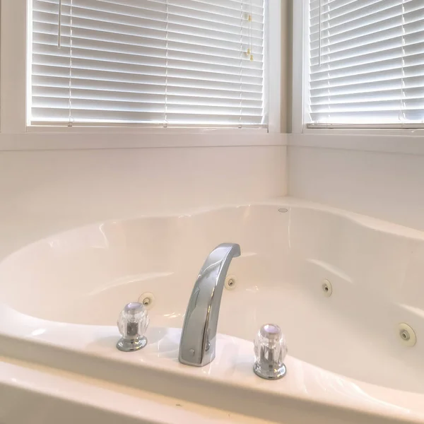 Square Close up of a gleaming white bathtub adjacent to the shower stall and windows — Stock Photo, Image