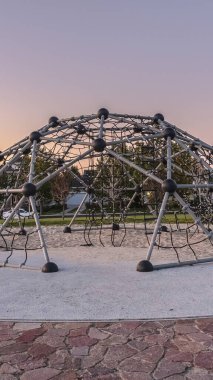 Günbatımında oyun parkında dikey çerçeve Metal tırmanma çerçevesi