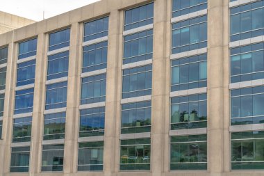 Modern ofis binası dış tarafı beton duvarlı ve büyük cam pencereli.